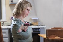 Femme atteinte du syndrome TAR utilisant une scie électrique à la maison — Photo de stock