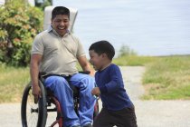 Латиноамериканец с травмой спинного мозга в инвалидном кресле играет со своим сыном — стоковое фото