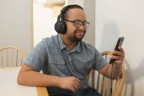 Щасливий афроамериканець людина з синдромом Дауна прослуховування музики з навушниками на дому — стокове фото