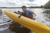Giovane con Sindrome di Down che si prepara ad usare un kayak in un lago — Foto stock