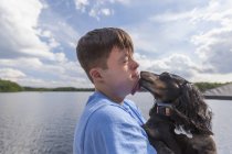 Jovem com Síndrome de Down brincando com um cachorro em uma doca — Fotografia de Stock