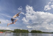 Молодий чоловік з синдромом Дауна стрибає в озеро. — стокове фото