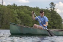 Молодой человек с синдромом Дауна гребёт на каноэ в озере — стоковое фото