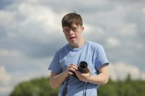 Jeune homme trisomique tenant une caméra — Photo de stock