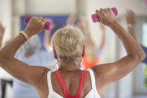 Visão traseira da mulher idosa se exercitando no ginásio — Fotografia de Stock