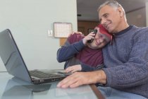 Padre con lesione del midollo spinale e figlio con sindrome di Down con computer portatile a casa — Foto stock