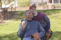 Отец с травмой спинного мозга и сын с синдромом Дауна собираются играть в бейсбол в парке — стоковое фото
