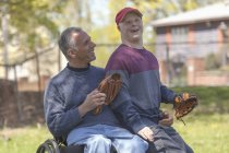 Father with Spinal Cord Injury and son with Down Syndrome about to play baseball in park — Stock Photo