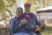 Отец с травмой спинного мозга и сын с синдромом Дауна собираются играть в бейсбол в парке — стоковое фото