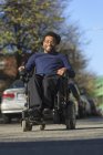Homem afro-americano feliz com paralisia cerebral usando sua cadeira de rodas poder fora — Fotografia de Stock