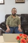 Glücklicher afrikanisch-amerikanischer Mann mit Down-Syndrom mit Laptop zu Hause — Stockfoto