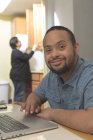 Felice uomo afroamericano con sindrome di Down utilizzando il computer portatile con la madre a casa — Foto stock