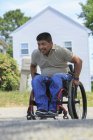 Hombre hispano con lesión de médula espinal en silla de ruedas frente a su casa - foto de stock