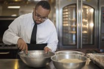 Афроамериканец с синдромом Дауна в качестве повара, готовящего на коммерческой кухне — стоковое фото