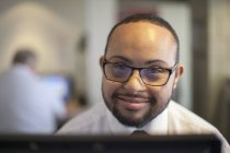 Hombre afroamericano feliz con síndrome de Down como camarero tomando reservas en la computadora - foto de stock