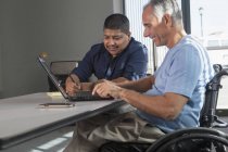 Due uomini con lesioni al midollo spinale che lavorano in un ufficio — Foto stock