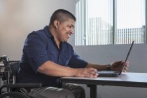 Homme hispanique avec lésion médullaire travaillant dans un bureau — Photo de stock