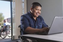 Homem hispânico em cadeira de rodas com lesão medular no trabalho — Fotografia de Stock