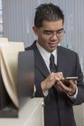 Hombre asiático con autismo trabajando en la oficina con teléfono inteligente - foto de stock
