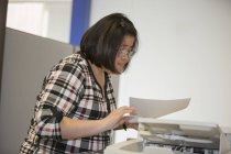 Asian woman with a Learning Disability working at a copy machine in office — Stock Photo