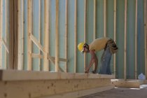 Carpinteiro colocando um parafuso prisioneiro em uma moldura de parede no local de construção do edifício — Fotografia de Stock