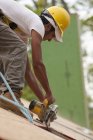 Falegname ispanico utilizzando una sega circolare sul pannello del tetto in una casa in costruzione — Foto stock