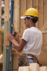 Carpinteiro hispânico marcando uma medida em uma placa em uma casa em construção — Fotografia de Stock
