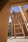 Carpinteiro hispânico usando uma pistola de pregos em uma casa em construção — Fotografia de Stock