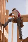 Carpintero hispano trabajando en el piso superior de una casa en construcción - foto de stock