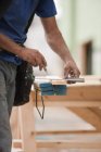 Hispanic carpenter measuring boards with a rafter square at a house under construction — Stock Photo