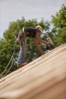 Charpentier hispanique utilisant un pistolet à ongles sur la toiture d'une maison en construction — Photo de stock