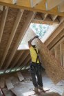 Charpentier soulevant un panneau de toit sur le chantier de construction — Photo de stock