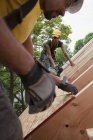 Charpentiers hispaniques mesurant et clouant panneau de toit à une maison en construction — Photo de stock