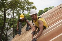 Carpinteiros hispânicos colocando painel de telhado em uma casa em construção — Fotografia de Stock