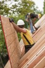 Carpinteiros hispânicos colocando painel de telhado em uma casa em construção — Fotografia de Stock