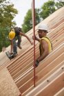 Carpinteiros levantando um painel de telhado no lugar em um telhado — Fotografia de Stock