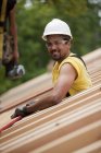 Charpentiers hispaniques plaçant le panneau de toit à une maison en construction — Photo de stock