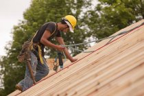 Carpenter using safety strap on the roof of a house under construction — Stock Photo