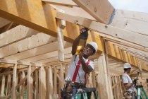 Carpintero usando una sierra en los tableros de una casa en construcción - foto de stock