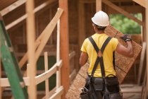 Hispanic carpenter holding a roof panel at a house under construction — Stock Photo
