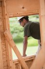 Hispanic carpenter looking out from the window opening of second floor at a house under construction — Stock Photo
