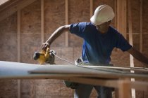 Carpenter using a circular saw at a building construction site — Stock Photo