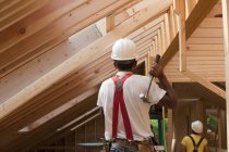 Hispanic carpenter using hammer on upper floor at a house under construction — Stock Photo