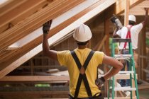 Hispanic carpenters working on roof beams at a house under construction — Stock Photo