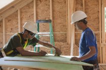 Carpenters measuring exterior sheathing at a construction site — Stock Photo