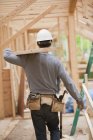 Carpinteiro hispânico carregando uma placa no andar superior em uma casa em construção — Fotografia de Stock