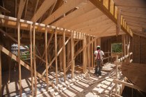 Carpintero hispano trabajando en planta alta en una casa en construcción - foto de stock