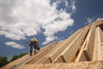 Плотник держит гвоздомет на крыше строящегося дома — стоковое фото