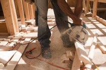 Hispanic carpenter using circular saw on board at a construction site — Stock Photo