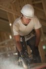 Carpenter using a circular saw on roof panel at a house under construction — Stock Photo